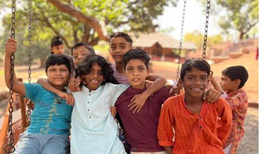 A group of boys smiling together on a swing